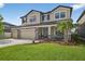 Beautiful two-story home with a three-car garage, stone accents, and a well-maintained front yard at 7570 Sweeter Tide Trl, Wesley Chapel, FL 33545