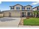 Charming two-story home featuring a three-car garage, stone accents, and manicured lawn at 7570 Sweeter Tide Trl, Wesley Chapel, FL 33545