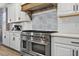 Chef's kitchen showcases a professional-grade range with custom hood and decorative backsplash adding a touch of elegance at 7570 Sweeter Tide Trl, Wesley Chapel, FL 33545