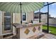 View of the outdoor kitchen featuring a grill under an umbrella in screened in enclosure at 7570 Sweeter Tide Trl, Wesley Chapel, FL 33545