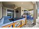 Covered patio featuring blue sectional, ceiling fan, mounted TV, outdoor seating, and brick floors at 7570 Sweeter Tide Trl, Wesley Chapel, FL 33545