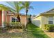Side yard with grass and landscaped plantings with mature palm trees and walkway to backyard at 7705 Nottinghill Sky Dr, Apollo Beach, FL 33572