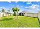 The fenced backyard features a well-maintained lawn, mature trees, and a view of the home's screened-in patio at 8174 Wheat Stone Dr, Zephyrhills, FL 33540