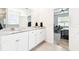 Light-filled bathroom featuring granite double vanity and open view to bedroom at 8174 Wheat Stone Dr, Zephyrhills, FL 33540