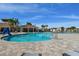 Expansive community pool area featuring a splash pad, a covered pavilion, palm trees, and comfortable lounge seating at 8174 Wheat Stone Dr, Zephyrhills, FL 33540