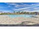 Large community pool surrounded by ample lounge seating, lush palm trees, and a secure fence on a sunny day at 8174 Wheat Stone Dr, Zephyrhills, FL 33540