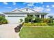 Charming single-story home with well-manicured lawn and landscaping under a clear, blue sky at 8174 Wheat Stone Dr, Zephyrhills, FL 33540