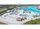 Community aerial view with white sand volleyball courts and a lagoon with lounge chairs, umbrellas and water slides at 8210 Juning Cv, Wesley Chapel, FL 33545