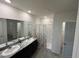 Spacious bathroom with dual sinks, granite countertops, and a walk-in shower with a neutral shower curtain at 8210 Juning Cv, Wesley Chapel, FL 33545