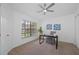 Well-lit home office with neutral carpet, ceiling fan and a view of the yard at 9751 Conservation Dr, New Port Richey, FL 34655