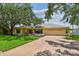 Inviting single-story home featuring a two-car garage, charming shutters, mature trees, and a well-manicured lawn at 1443 54Th Ne Ave, St Petersburg, FL 33703
