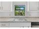 Kitchen sink area features granite countertops, stylish faucet, decorative window, and white cabinetry at 12004 Legacy Bright St, Riverview, FL 33578