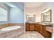Luxurious bathroom with a large soaking tub, dual vanities, and granite countertops at 1208 Carriage Park Dr, Valrico, FL 33594