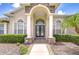 Elegant front entrance with stone accents, an arched doorway, and manicured landscaping at 1208 Carriage Park Dr, Valrico, FL 33594