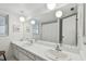 Bright bathroom with double sinks, a large mirror with globe lighting fixtures and white cabinetry at 1270 Inverness, Dunedin, FL 34698