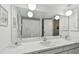 Bright bathroom features double sinks, a large mirror with globe lighting and neutral walls and cabinetry at 1270 Inverness, Dunedin, FL 34698