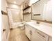 Updated bathroom showcasing a white vanity, framed mirror, open shelves, and a tub with a shower at 12862 Rangeland Blvd, Odessa, FL 33556
