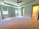 Main bedroom with two windows, tray ceiling, en-suite bathroom, and neutral carpet flooring at 12862 Rangeland Blvd, Odessa, FL 33556