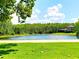 Scenic view of a tranquil pond surrounded by lush greenery and a home at 12862 Rangeland Blvd, Odessa, FL 33556