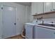 Bright laundry room with white washer and dryer, cabinets, and wood-look floors at 13029 111Th Ln, Largo, FL 33778