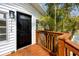 A charming entrance with a black front door, a newly stained wood deck, and tropical landscaping at 13148 3Rd E St, Madeira Beach, FL 33708
