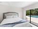 Bright bedroom featuring a queen bed, a blue blanket, and a sliding glass door to the pool at 13501 Avista Dr, Tampa, FL 33624