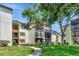 Beautiful condo building with manicured lawn and mature trees against a sunny sky at 14130 Rosemary Ln # 3202, Largo, FL 33774