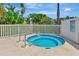 Inviting in-ground hot tub with steel handrails, surrounded by lush tropical greenery and a secure white fence at 14130 Rosemary Ln # 3202, Largo, FL 33774