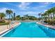 A pristine community swimming pool with crystal blue waters and poolside seating under a bright sunny sky at 14130 Rosemary Ln # 3202, Largo, FL 33774