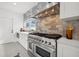 Gourmet kitchen with professional range, stainless steel hood, white cabinets, and tiled backsplash at 1650 22Nd N Ave, St Petersburg, FL 33713