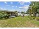 Lush backyard with a screened-in patio, patio area with seating, mature trees and a well-manicured lawn at 1707 Cardinal Dr, Clearwater, FL 33759
