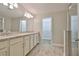 Bathroom with double sinks, granite countertops, wood-look tile floor, and access to walk-in closet at 17834 Althea Blue Pl, Lutz, FL 33558