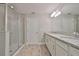 Bathroom featuring double sinks, granite countertops, tile floor, shower, and linen closet at 17834 Althea Blue Pl, Lutz, FL 33558