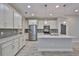 Modern kitchen with white cabinets, stainless appliances, granite counters, gray backsplash, and island at 17834 Althea Blue Pl, Lutz, FL 33558