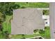 Aerial view of a tan house with a complex roof design, surrounded by lush greenery and a driveway with a car at 2032 Inverness Greens Dr # 76, Sun City Center, FL 33573