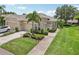 A well-maintained exterior of a beige residential building with a two-car garage, landscaping, and a driveway with car at 2032 Inverness Greens Dr # 76, Sun City Center, FL 33573