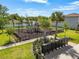 Community playground with modern play structures, black fence, and tropical landscaping next to community mailboxes at 221 Fairmont Dr, Spring Hill, FL 34609