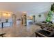Open-concept living room with tile floors, hanging plants, and stylish furnishings and partial kitchen view at 2525 W Bay Dr # B43, Belleair Bluffs, FL 33770