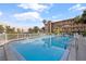 Swimming pool with pool furniture, palm trees and condo building in the background at 2525 W Bay Dr # B43, Belleair Bluffs, FL 33770
