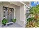 Cozy front porch showcasing a black front door with decorative sunflower wreaths and potted plants at 26972 Evergreen Chase Dr, Wesley Chapel, FL 33544