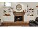 Living room fireplace with stone surround flanked by built-in shelving and wood floors at 2806 Fairway View Dr, Valrico, FL 33596
