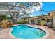 Screened-in pool with a waterfall feature, hot tub, and stone paver deck at 2806 Fairway View Dr, Valrico, FL 33596