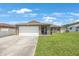 Charming single-story home featuring a two-car garage, stone accents, and a well-manicured lawn under a bright sky at 3301 Tuckahoe Pl, Holiday, FL 34690