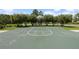An open-air basketball court with a hoop, surrounded by trees and green grass at 33075 Kateland Dr, Wesley Chapel, FL 33545