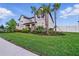 A well-maintained front yard with lush grass and trimmed bushes leading up to a home with palm trees at 33075 Kateland Dr, Wesley Chapel, FL 33545