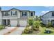 Townhome exterior with a two-car garage, well-manicured lawn, and green landscaping at 36414 Well Hill Way, Zephyrhills, FL 33541
