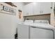 Functional laundry room featuring a washer, dryer, and overhead storage cabinets at 36414 Well Hill Way, Zephyrhills, FL 33541