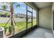 View from screened-in patio to fenced backyard with green grass and palm trees, perfect for outdoor relaxation at 36414 Well Hill Way, Zephyrhills, FL 33541