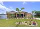 Beautifully landscaped home featuring a well-manicured lawn, vibrant flower beds, and mature palm trees at 386 Westwinds Dr, Palm Harbor, FL 34683