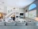 Spacious living room featuring a ceiling fan, large windows, staircase, and modern fireplace at 386 Westwinds Dr, Palm Harbor, FL 34683
